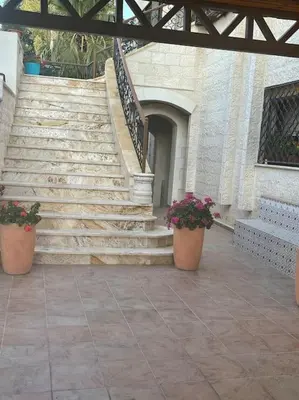 a set of stairs with two potted plants in front of a building at Sunset Balcony Retreat - Spacious and Comfortable 2 Bedrooms 2 Bathrooms in Amman
