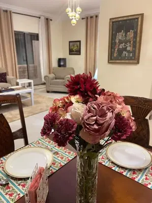 a vase of flowers on a table in a living room at Sunset Balcony Retreat - Spacious and Comfortable 2 Bedrooms 2 Bathrooms in Amman