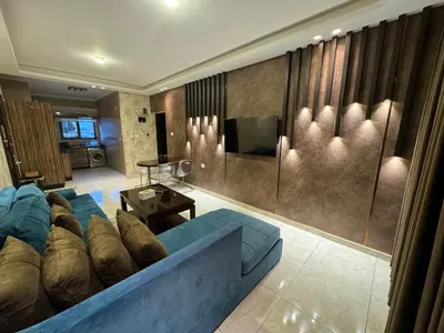 a living room with a blue couch and a television at COZY apt For long &short Stay in Amman