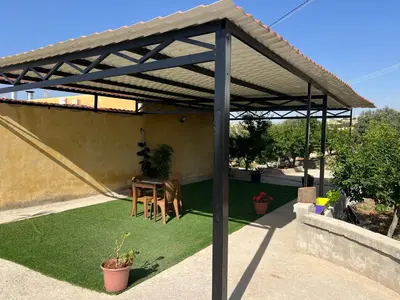 a wooden pergola with a table on a lawn at شاليه جبال سوف in Jerash