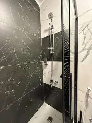 a bathroom with a shower with black marble walls at Stylish Luxe Apartment F-R 0003 in Amman