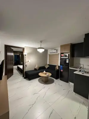a living room with a black couch and a kitchen at Stylish Luxe Apartment F-R 0006 in Amman