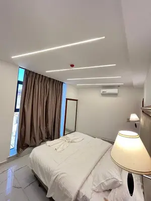 a bedroom with a white bed with a lamp and a window at Jerash Hotel in Jerash