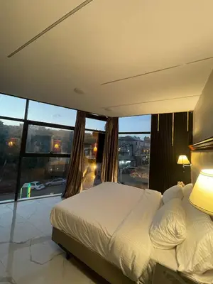 a bedroom with a white bed and a large window at Jerash Hotel in Jerash