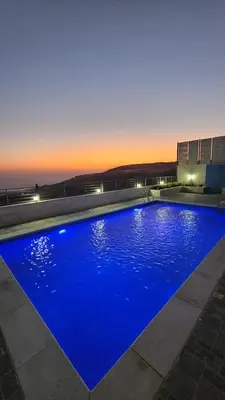 a large blue swimming pool with a sunset in the background at Ayla Chalets in Amman