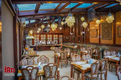 a restaurant with wooden tables and chairs and chandeliers at Jad Hotel & Suite in Umm Uthainah