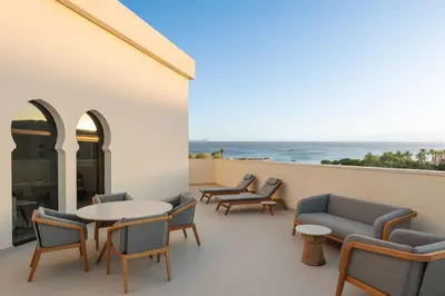 a balcony with chairs and tables and a view of the ocean at The Westin Saraya Aqaba Resort & Spa in Aqaba