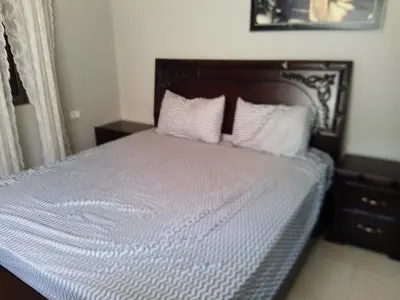 a bed with white sheets and pillows in a bedroom at Ayola Apartment in Madaba
