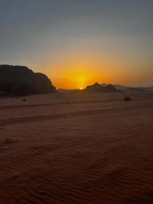 a sunset in the desert with the sun setting at Titanic Wadi Rum in Disah