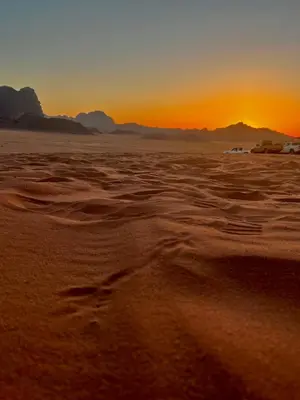 a sunset in the desert with tracks in the sand at Titanic Wadi Rum in Disah