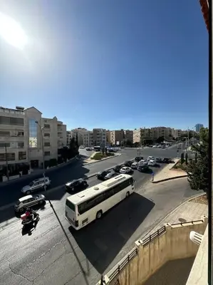 a white bus driving down a city street with cars at abdoun rooftop 1bedroom kh&sh 03 in Amman