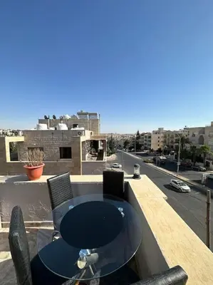 a table on a balcony with a view of a city at abdoun rooftop 1bedroom kh&sh 03 in Amman