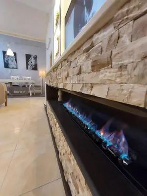 a fireplace in a living room with a stone wall at The heart of Jabal alweibdeh 2,000 SF entire apartment in Amman