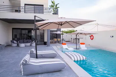a pool with chairs and umbrellas next to a building at The Gray Villas in Sowayma
