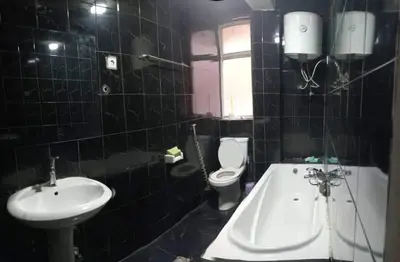 a black tiled bathroom with a sink and a toilet at Go there Inn in Az Zarqa