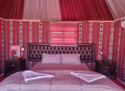a bedroom with a large bed with a red wall at Msek wadi rum camp in Disah
