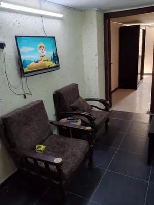 a room with two chairs and a tv on the wall at شقة الراحة و الهدوء economic comfortable flat in Amman