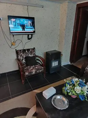 a living room with a tv and a chair and a table at شقة الراحة و الهدوء economic comfortable flat in Amman