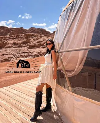 a woman in a white dress and black boots at ROYAL MOON BUBBLES lUXURY CAMP in Wadi Rum