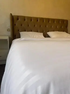 a large bed with white sheets and a large headboard at زهرة المدائن in Jerash