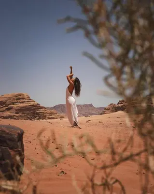 a woman is standing in the sand in the desert at MOON RUM lUXURY CAMP in Wadi Rum