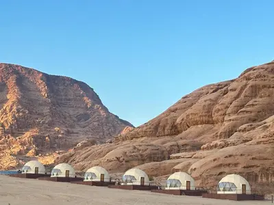 a group of domes in front of a mountain at Wadi Rum Neom camp in Wadi Rum