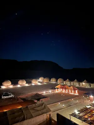 a view of a desert at night with lights at Ram Al-Umda Luxury Camp in Wadi Rum
