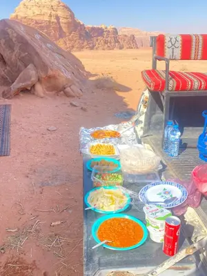 a table with food on it in the desert at Ram Al-Umda Luxury Camp in Wadi Rum