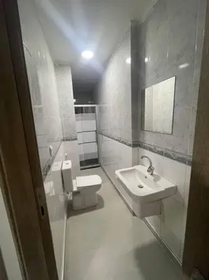 a white bathroom with a toilet and a sink at شقارى 9 in Ţāb Kirā‘