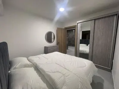 a bedroom with a white bed and a mirror at شقارى 9 in Ţāb Kirā‘