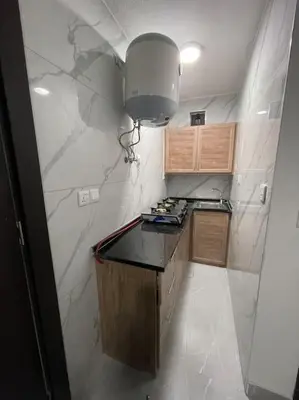 a small kitchen with a black counter and a light at شقارى 10 in Ţāb Kirā‘