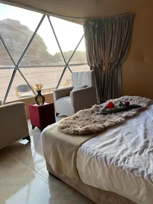 a bedroom with a bed and a large window at Royal Dunes Camp in Wadi Rum