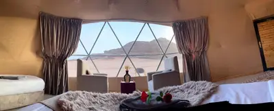 a bedroom with a large window with a view of the desert at Royal Dunes Camp in Wadi Rum