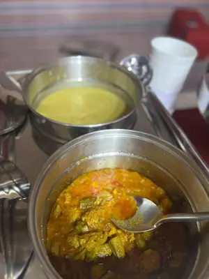 two metal pots of food with a spoon in it at Royal Dunes Camp in Wadi Rum