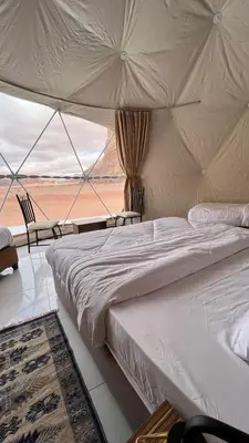 a bed in a tent with a view of the desert at RUM MAGIC SANDS BuBBLES CAMP in Wadi Rum