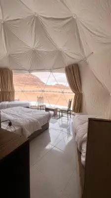a bedroom with two beds and a large window at RUM MAGIC SANDS BuBBLES CAMP in Wadi Rum
