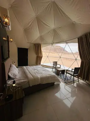 a bedroom with a bed and a large window at RUM MAGIC SANDS BuBBLES CAMP in Wadi Rum