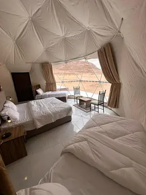 a bedroom with two beds and a large window at RUM MAGIC SANDS BuBBLES CAMP in Wadi Rum