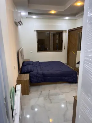 a bedroom with a blue bed and a mirror at شقة مفروشة و جديدة مع كراج للسيارة في ارقى مناطق اربد in Irbid