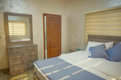 a bedroom with a bed and a dresser and a mirror at Tallet falastin in Umm Juraysāt