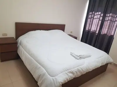 a white bed with a pair of shoes on it at Apartment in Amman Khalda in Amman