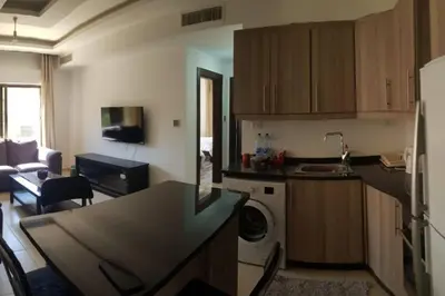 a kitchen with a washer and a living room at Apartment in Amman Abdoun area in Amman