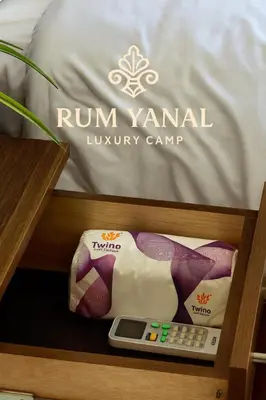 a drawer with a bed with a mattress and a remote control at RUM YANAL lUXURY CAMP in Wadi Rum