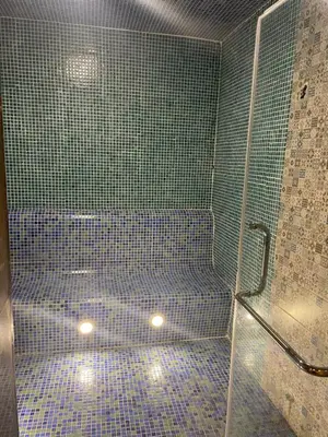 a bathroom with a shower with blue tiles at Modern Rooftop apartment in Amman