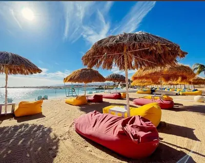 a beach with many chairs and umbrellas and the ocean at Ayla Apartment in Aqaba