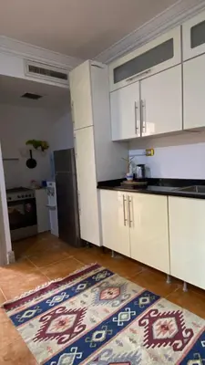 a kitchen with white cabinets and a rug on the floor at SeaStar Sea View apartment 10 minutes away from beach in Sowayma
