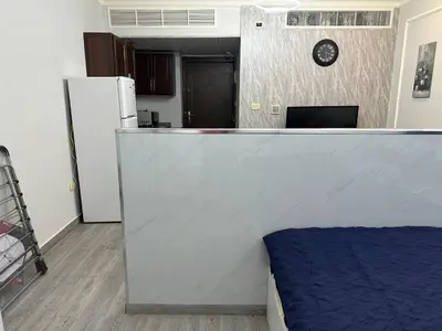 a room with a counter with a refrigerator and a clock at استوديو مفروش لشخصين الجاردنز 320 in Amman