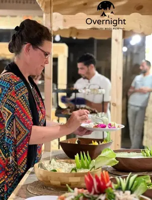 a woman holding a plate of food at a buffet at Rum Overnight luxury& jeep in Wadi Rum