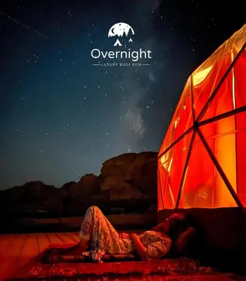 a person laying on a bed next to a tent at Rum Overnight luxury& jeep in Wadi Rum