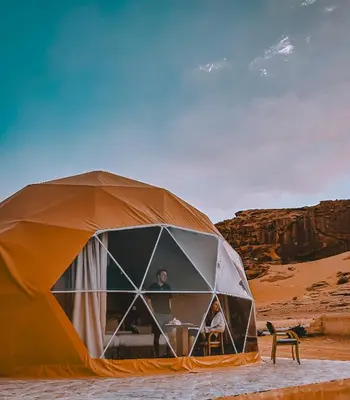 a man standing inside of a tent in the desert at Rum thabit camp in Wadi Rum